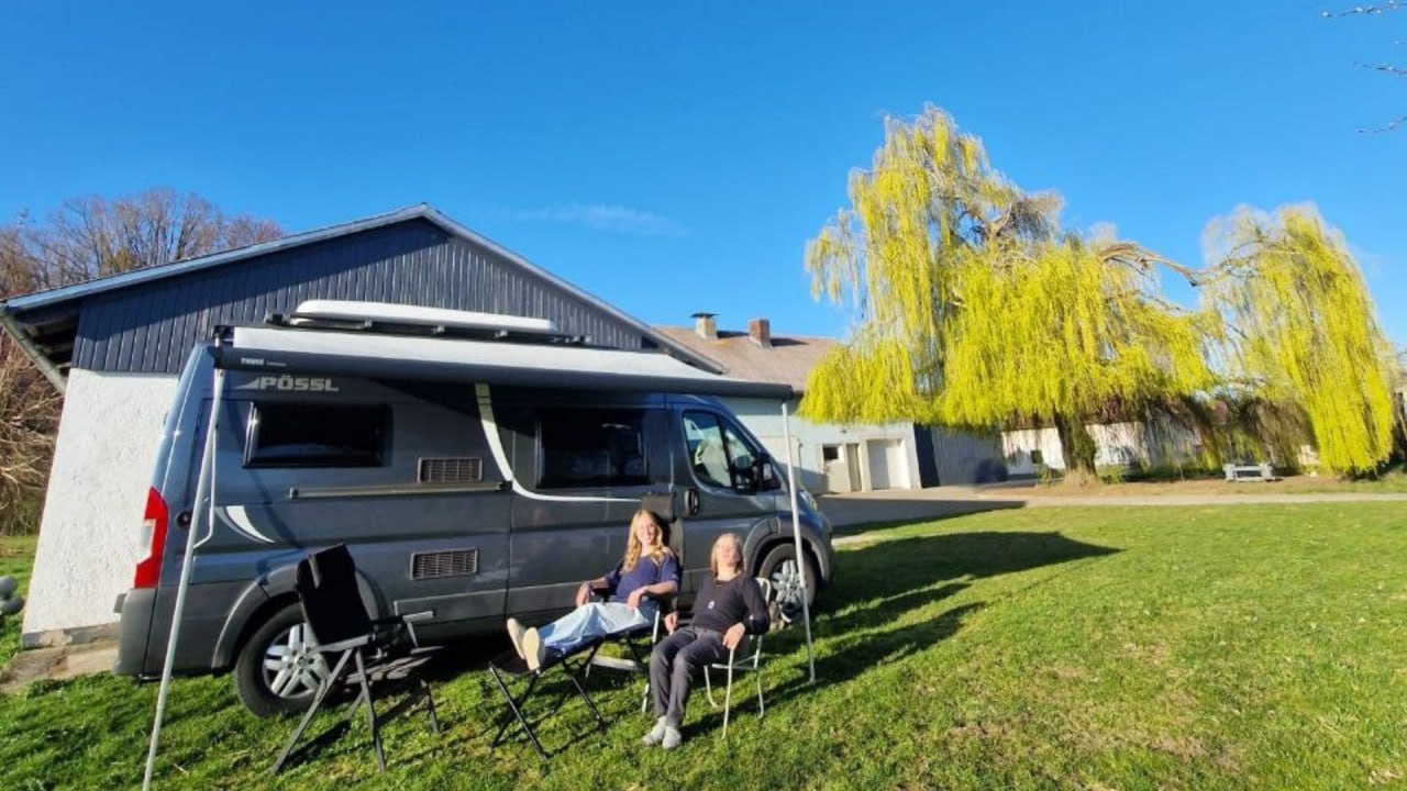 Zwei Reisende entspannen in der Sonne vor ihrem Campervan